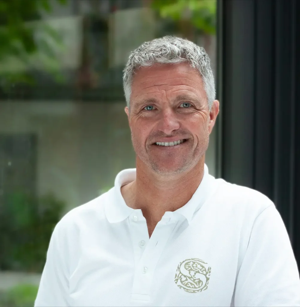 Porträt von Ralf Schumacher, lächelnder Keynote Speaker im Bereich Motorsport in weißem Polohemd